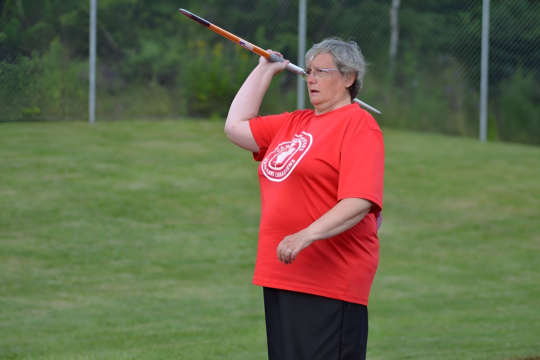 Photo of Jane Warren wearing a red shirt and preparing to throw a spear