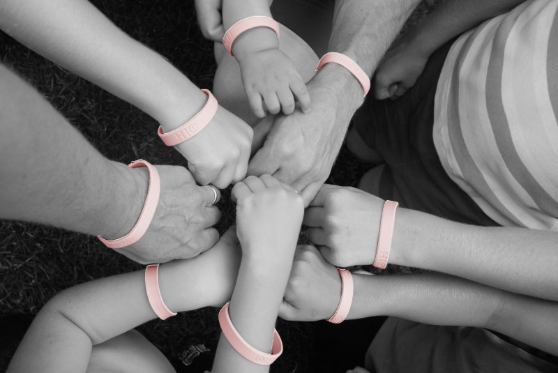 Family hands with pink bracelets for breast cancer