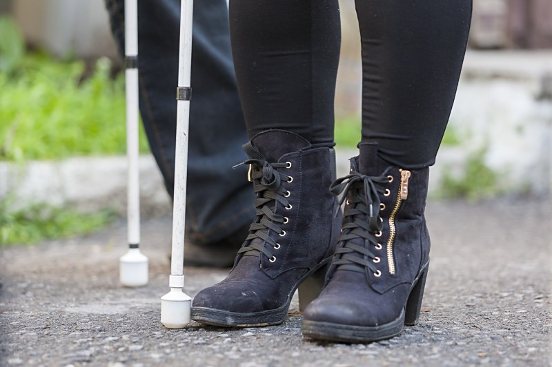 Feet of a woman wearing black boots with a cane